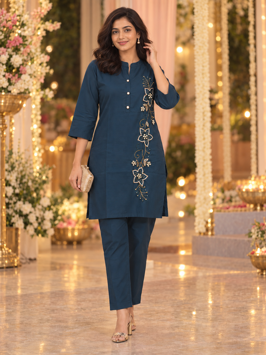 Teal-blue muslin co-ord set for women with floral pearlwork, a band-collar button-down top and matching straight-fit trousers.
