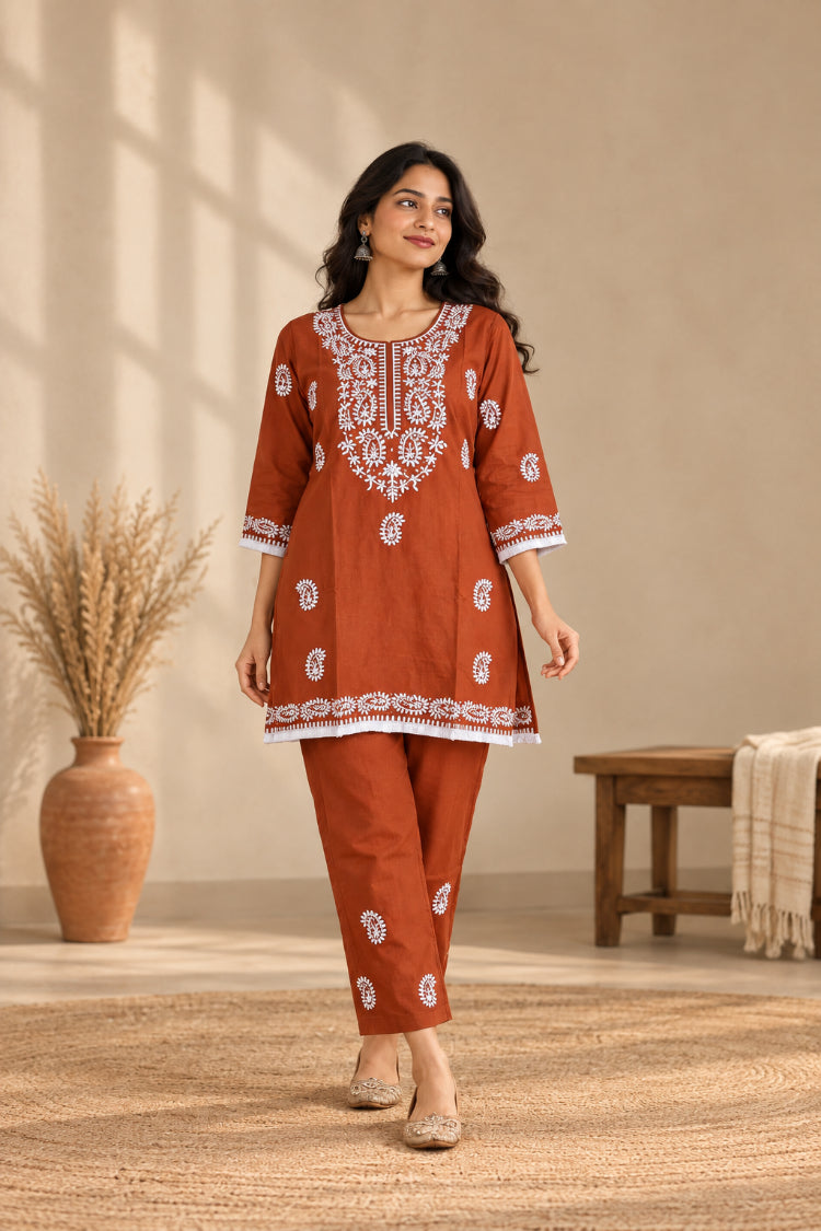 Rust chikankari style embroidered cotton co-ord set with white paisley thread work tunic and straight pants on hangers