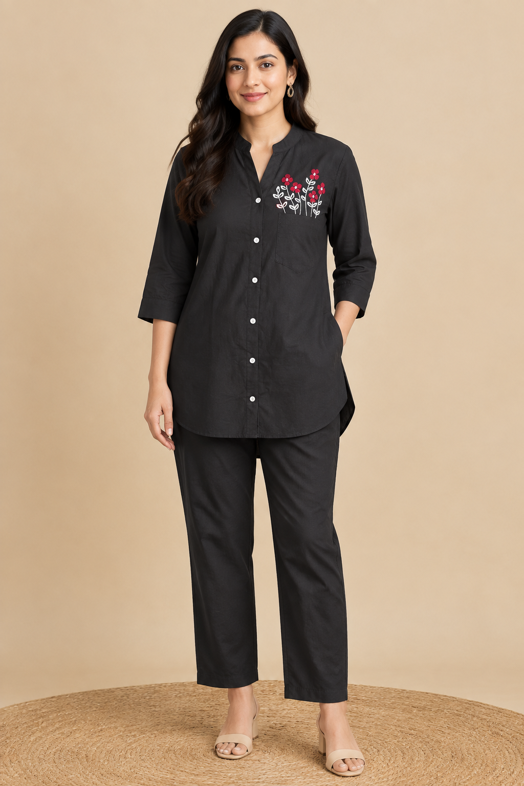 Black cotton shirt-style co-ord set with red floral embroidery above the chest pocket and matching straight pants on hangers
